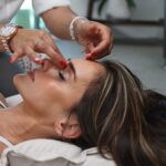 Eine liegende Frau erhält von einem Therapeuten Akupunkturnadeln in die Stirn.