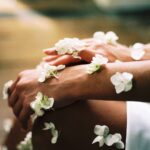 Mit weißen Blumen geschmückte Hände und Beine, die in sanftem, natürlichem Licht sanft aufeinander ruhen - eine heitere Szene, die die Essenz von Spa-Wellness einfängt.