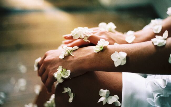 Mit weißen Blumen geschmückte Hände und Beine, die in sanftem, natürlichem Licht sanft aufeinander ruhen - eine heitere Szene, die die Essenz von Spa-Wellness einfängt.