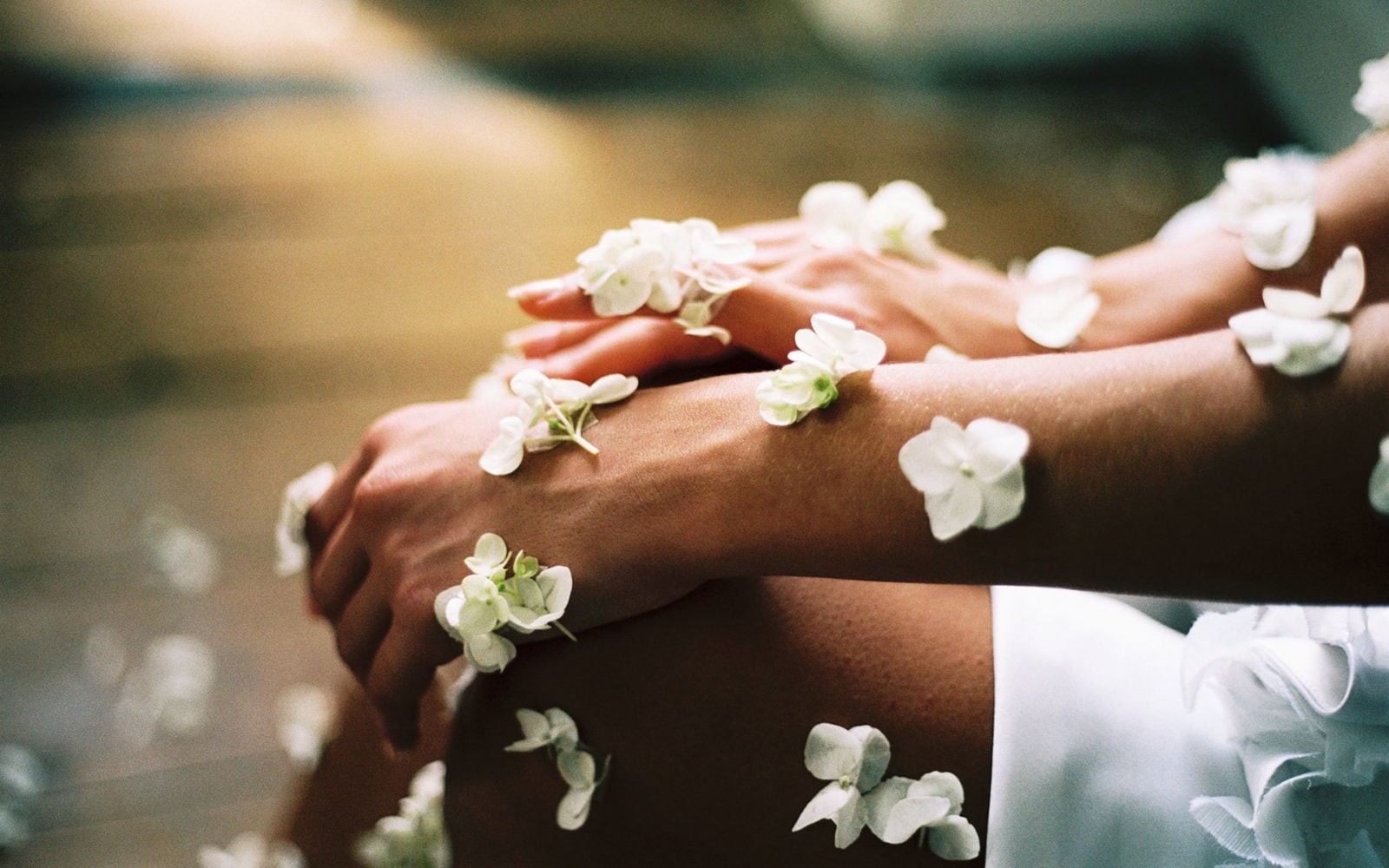 Mit weißen Blumen geschmückte Hände und Beine, die in sanftem, natürlichem Licht sanft aufeinander ruhen - eine heitere Szene, die die Essenz von Spa-Wellness einfängt.