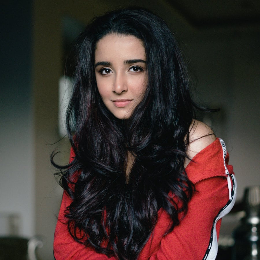 Frau mit langen dunklen Haaren, die ein rotes Oberteil trägt und mit einem sanften Lächeln in die Kamera blickt, aufgenommen im echten Leonardo Black Stil.