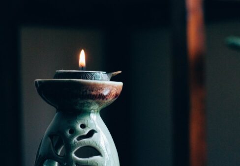 Eine brennende Teelichtkerze in einem dekorativen Halter, die in einem schwach beleuchteten Raum sanft leuchtet.