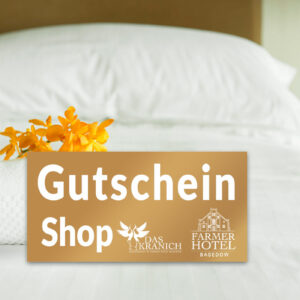 Ein Gutschein liegt auf einem Bett mit einem Handtuch und orangefarbenen Blumen.
