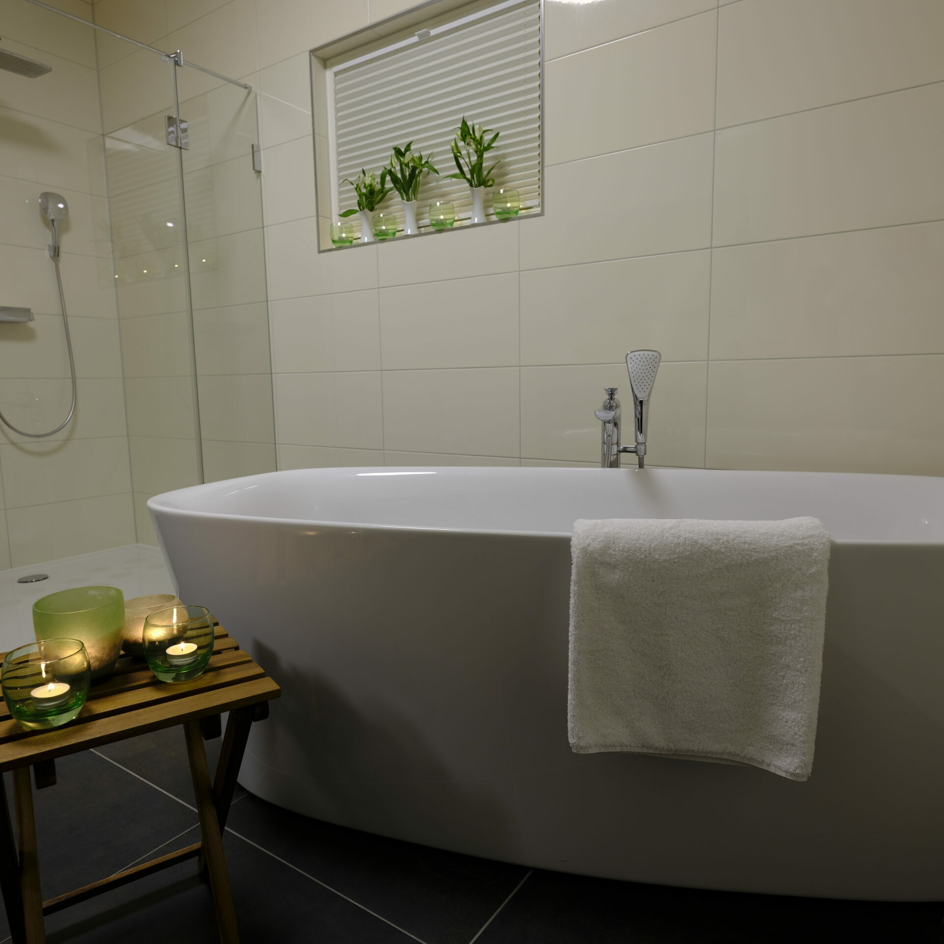 Modernes Badezimmer in der Farmer Suite mit weißer Wanne, Handtuch, Kerzen auf einem Holzhocker und Topfpflanzen auf der Fensterbank.