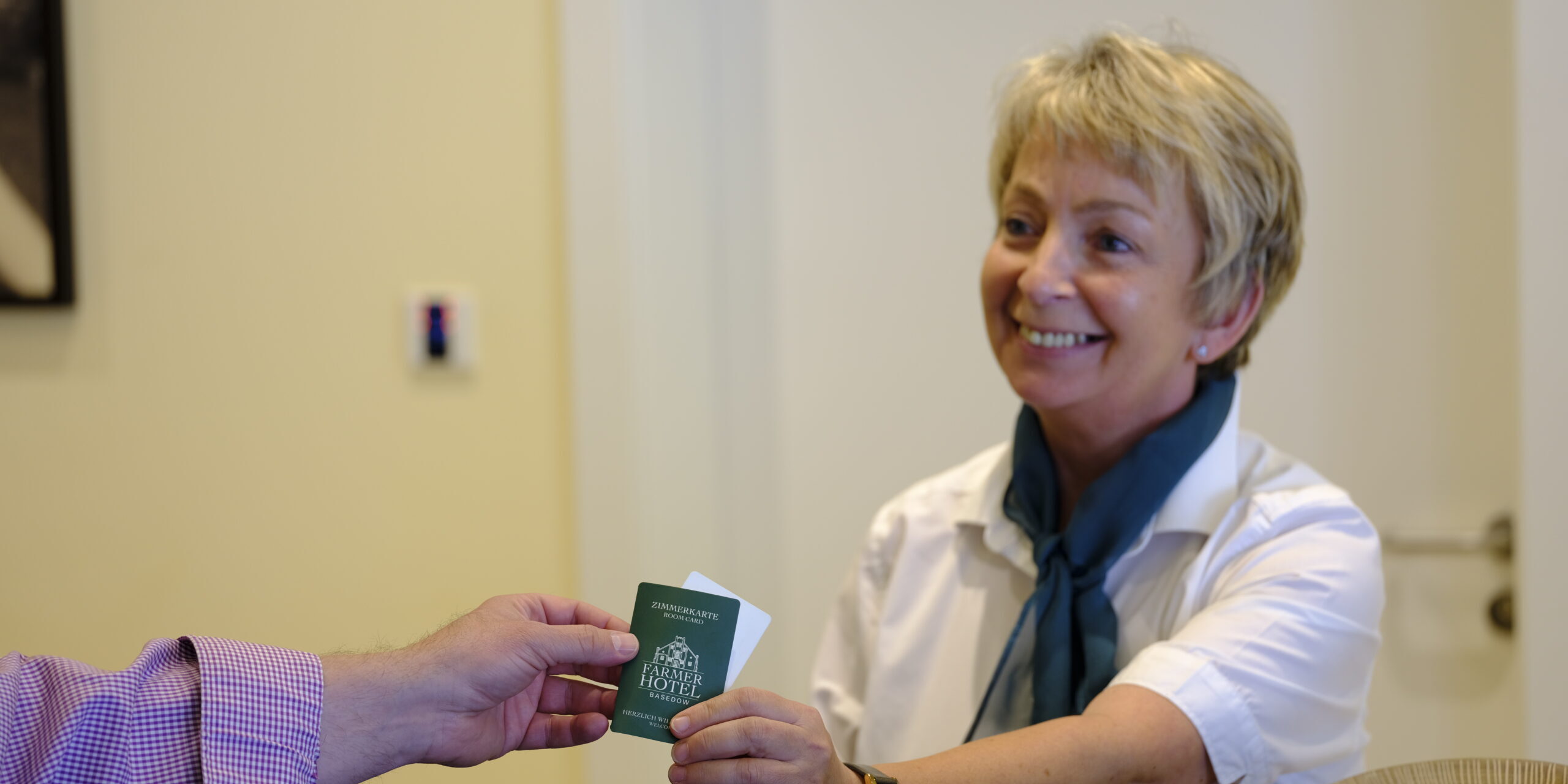 Eine lächelnde Rezeptionistin überreicht einem Gast an der Hotelrezeption eine Schlüsselkarte und schafft so warme Impressionen für ankommende Besucher. Eine lächelnde Rezeptionistin überreicht einem Gast an der Hotelrezeption eine Schlüsselkarte und schafft so warme Impressionen für ankommende Besucher.