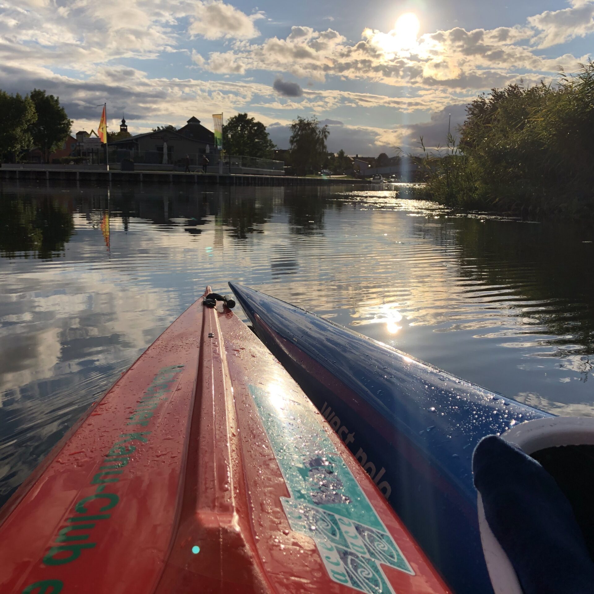 Zwei Kajaks auf einem ruhigen See bei Sonnenuntergang, mit den Spiegelungen von Wolken und Bäumen auf dem Wasser – eine friedliche Szene, die an beschauliche Reittage am Marstall erinnert, wo Natur und stille Abenteuer auf einen warten.