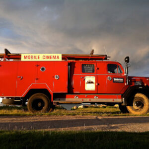 Ein leuchtend roter Truck mit der Aufschrift WanderKino Mobile Cinema steht unter freiem Himmel und lädt Kinofreunde mit einem Ticket "WanderKino 2026" zu einem unvergesslichen Filmerlebnis ein.