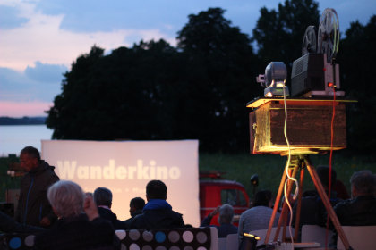 Genießen Sie die Magie des Kinos unter freiem Himmel - schnappen Sie sich Ihr Ticket für das "WanderKino 2026", eine Filmvorführung unter freiem Himmel in der Abenddämmerung, bei der Menschen zusammenkommen, um Filme auf einer großen Leinwand zu erleben.