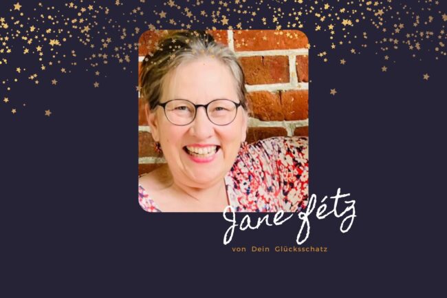 Lächelnde Frau mit Brille vor einer Backsteinmauer, darüber goldene Sterne; der Text lautet: Jane Jetz von Dein Glücksschatz – präsentiert das exklusive Glücks-Arrangement.
